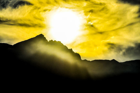 A mountain range with a sun in the skyの写真素材
