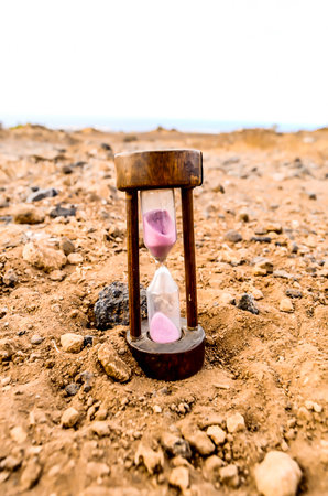 A sand timer is sitting on a rocky surfaceの写真素材