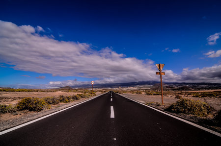 A long, empty road with a few trees in the backgroundの写真素材