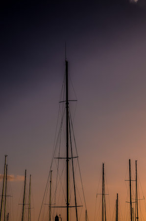 A group of tall poles with sails on them are silhouetted against a purple skyの写真素材