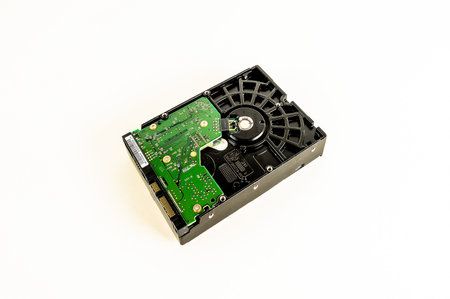 A black and green hard drive sits on a white background. The green part of the drive is the hard drive's platterの写真素材