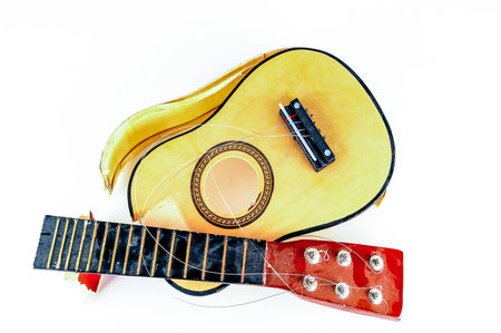 A guitar is on top of a ukulele. The guitar is yellow and the ukulele is redの写真素材