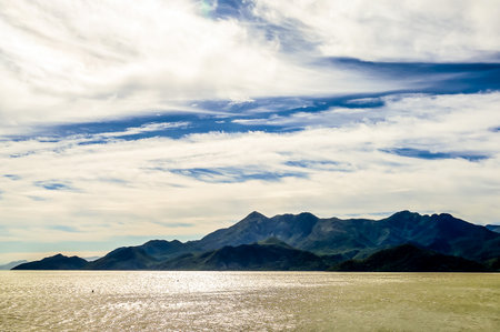 A beautiful mountain range is visible in the distance, with a clear blue sky and a calm ocean. The scene is serene and peaceful, with the mountains and ocean creating a sense of tranquilityの写真素材
