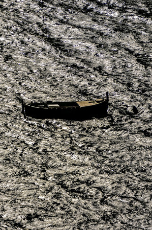 A boat is floating on a body of water. The water is murky and the boat is smallの写真素材