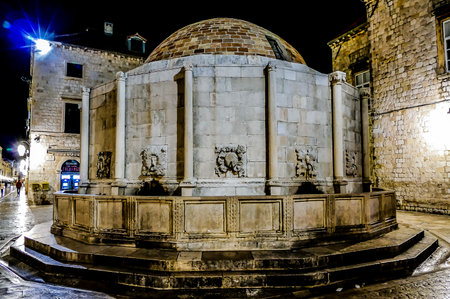 A large stone building with a dome on top. The building is surrounded by a stone wall. The building is lit up at nightの写真素材