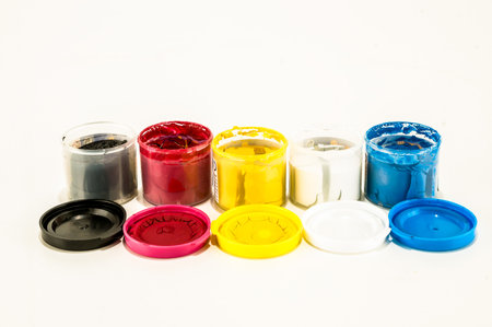 A row of paint cans with different colors. The colors are red, yellow, blue, green, and blackの写真素材