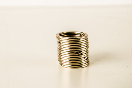A stack of silver coins is sitting on a white surface. The coins are arranged in a spiral pattern, with each coin overlapping the one below it. Concept of order and organizationの写真素材