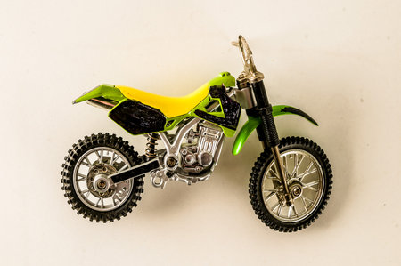 A green and yellow motorcycle with black tires. The motorcycle is on a white wall. The motorcycle is a toy and is not in useの写真素材