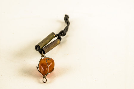 A necklace with a stone and a metal piece. The stone is orange and the metal piece is brownの写真素材