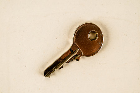 A key is shown on a white background. The key is silver and has a hole in the centerの写真素材