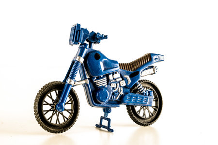 A blue toy motorcycle with a black seat and a black handlebar. The motorcycle is sitting on a white surfaceの写真素材