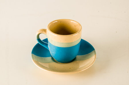 A blue and white coffee cup sits on a white plate. The cup is empty and the plate is cleanの写真素材
