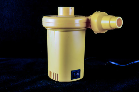 A yellow device with a black background. The device is plugged into a wall outlet.の写真素材