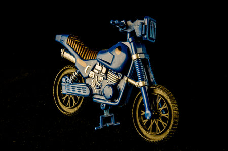 A blue motorcycle with a black seat and a black headlight. The motorcycle is parked on a dark backgroundの写真素材