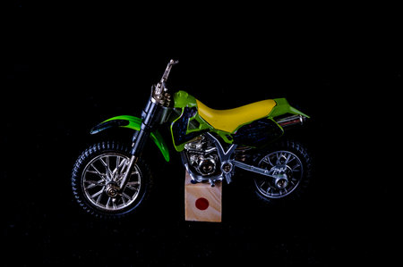 A green and yellow motorcycle is sitting on a wooden block. The motorcycle is a model and is not in motionの写真素材