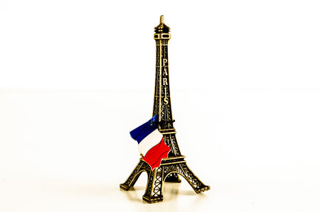 A small model of the Eiffel Tower with a flag on top. The flag is red, white, and blueの写真素材