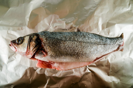 A fish is on a piece of foil. The fish is cut in half.の写真素材