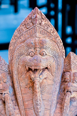 A carved wooden sculpture of a snake with a mouth open. The sculpture is brown and has a lot of detailの写真素材