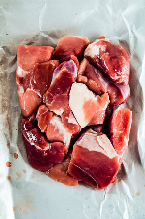 A piece of meat is cut into small pieces and is on a piece of paper. The meat is raw.の写真素材