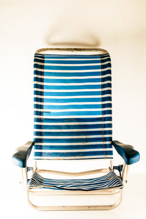 A blue and white striped chair is sitting on a white background. The chair is empty and has a casual, relaxed vibeの写真素材