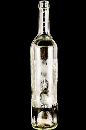 A bottle of wine is shown in a black background. The bottle is empty and the label is missing. Concept of emptiness and loss, as the wine bottle is no longer filled with its contentsの写真素材