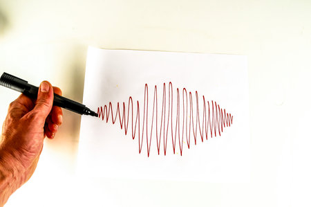 A person is drawing a red line on a white piece of paper with a marker. Concept of creativity and artistic expression, as the person is using the marker to create a uniqueの写真素材