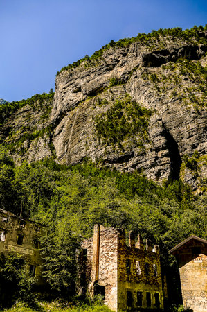 A mountain with a building in the foreground. The building is old and has a stone facade. The mountain is covered in trees and the sky is clearの写真素材