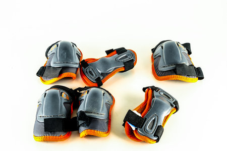 A row of knee pads are lined up on a white background. The pads are orange and grayの写真素材