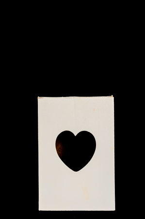 A white box with a heart cut out of it. The heart is cut out of the box, leaving a small opening. The box is placed on a black backgroundの写真素材