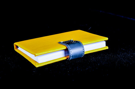 A yellow book with a black cover. The book is open to a page.の写真素材