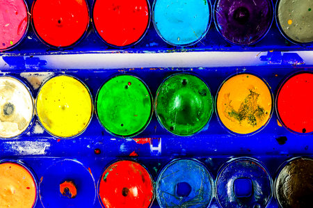 A blue box with many different colored paint tubes inside. The tubes are all different colors and sizesの写真素材