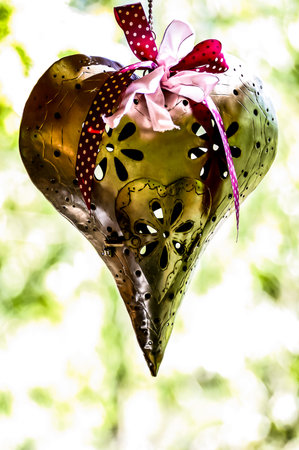 A heart shaped ornament with a red ribbon hanging from it. The ribbon is tied in a bowの写真素材