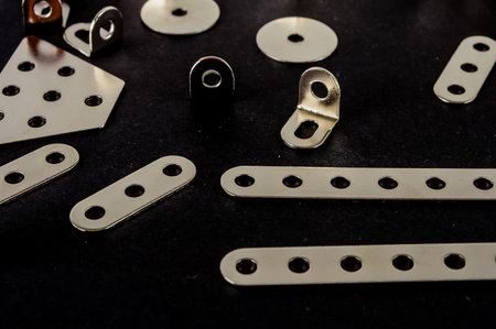 A collection of metal pieces with holes in them. The pieces are of different shapes and sizes, and they are arranged on a black background. Concept of organization and precisionの写真素材