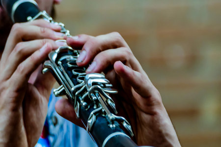 A man is playing a black clarinet. Concept of skill and passion as the musician expertly plays the instrument. The black color of the clarinet adds a touch of elegance and sophistication to the sceneの写真素材