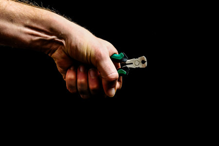 Cutter Pliers and a Hand on a Black Backgroundの写真素材