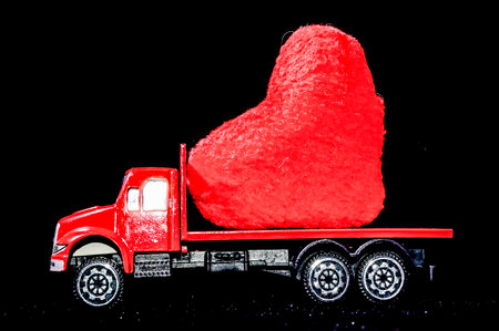 A red truck carrying a heart-shaped object.の写真素材
