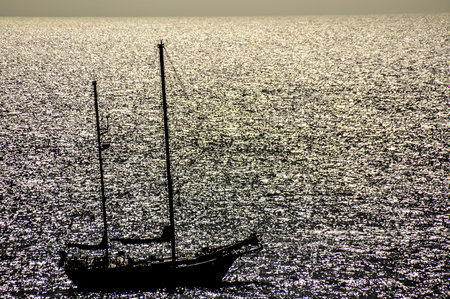 Backlight Picture of a Silhouette Boat in the Oceanの写真素材