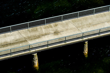 A bridge over a body of water with a railing. The bridge is made of concrete and is very longの写真素材