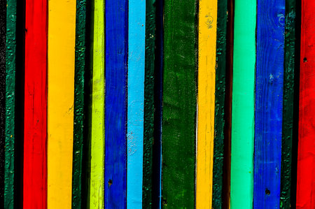 A colorful wooden fence with green, blue, and yellow stripes. The fence is made of wood and has a rustic lookの写真素材