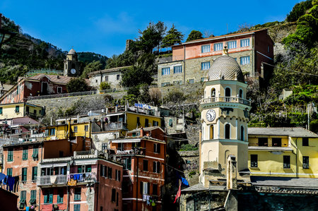 A small town with a clock tower in the center. The buildings are colorful and the sky is blueの写真素材