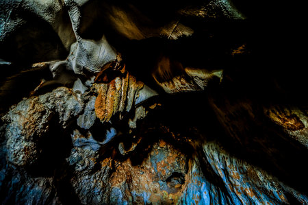 A dark cave with a lot of rock formations and a lot of dirt. The cave is very dark and the colors are mostly brown and blueの写真素材