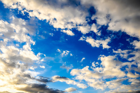 The sky is blue with a few clouds scattered throughout. The clouds are white and fluffy, and they are spread out across the sky. Scene is peaceful and serene, like the cloudsの写真素材