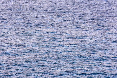 A blurry image of the ocean. The water appears to be choppy and rough, with a lot of white foam on the surface. The image has a sense of movement and energyの写真素材