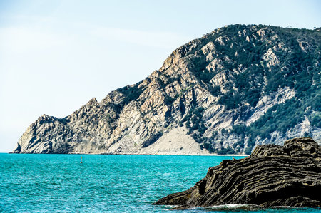 A rocky shoreline with a blue ocean in the background. The ocean is calm and the rocks are jaggedの写真素材