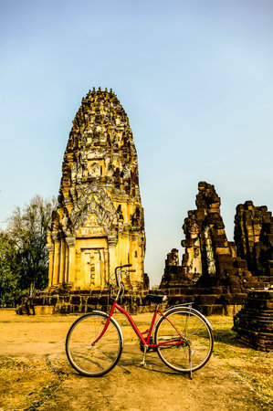 A red bicycle is parked in front of a large building. The scene is peaceful and serene, with the bike and the building creating a sense of calmnessの写真素材