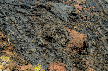 A rocky hillside with a lot of brown and black rocks. The rocks are scattered all over the hill and some of them are small and round. The hillside has a rugged and rocky appearanceの写真素材