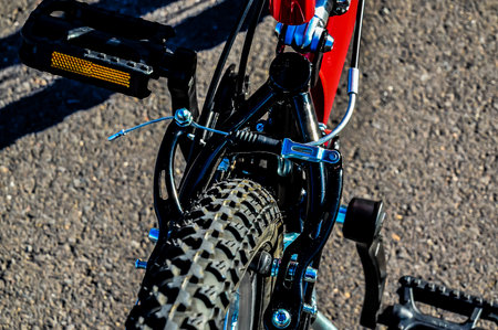 A red bicycle with a black seat and black pedals. The bike is parked on the groundの写真素材
