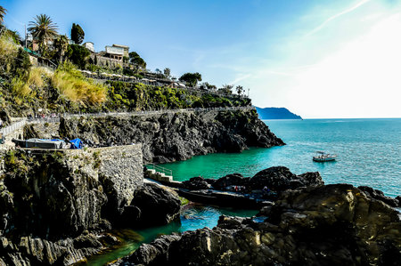 A rocky shoreline with a small body of water and a few boats. The water is a deep blue colorの写真素材