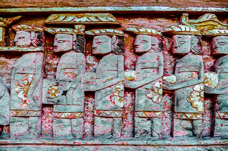 A group of people are depicted in a stone carving, with some of them holding flowers. The scene gives off a sense of reverence and respect for the people in the carvingの写真素材