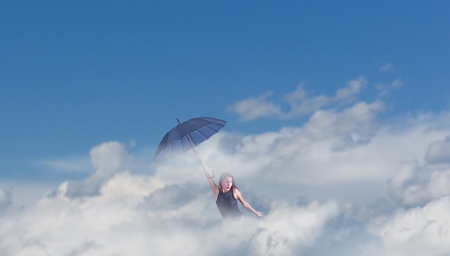 Flying girl with umbrella in the blue blue sky の写真素材